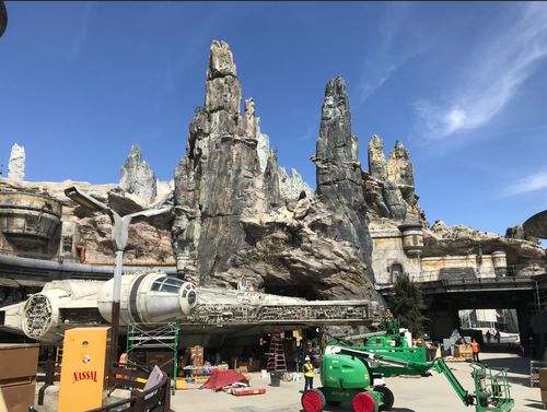 Sar Wars: Galaxy's Edge under construction with SkyJacks in front of the Millenium Falcon.