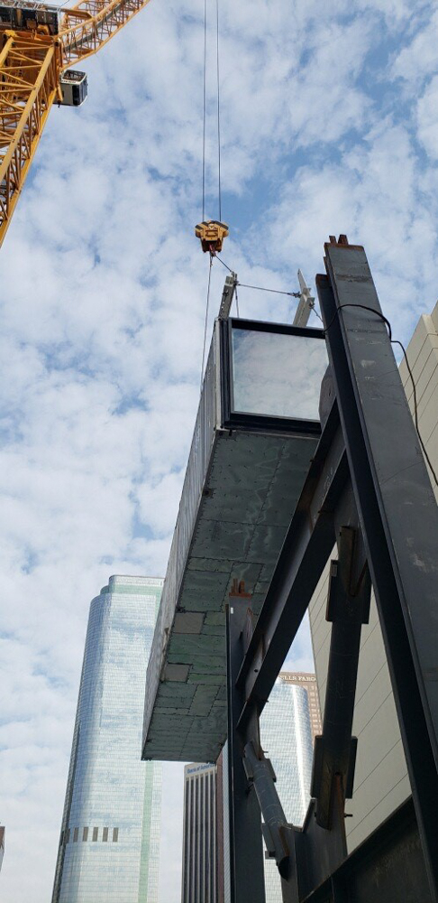 A modular room being lifted into place on a steel frame.