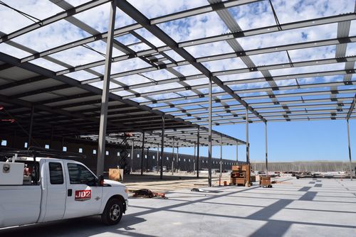 A JD2 truck in a warehouse under construction with the roof being completed up it.