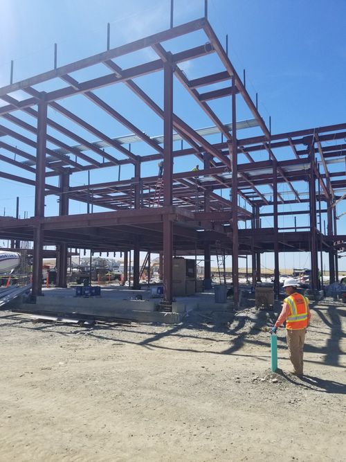 A construction worker walking towards the steel frame construction of the new school.