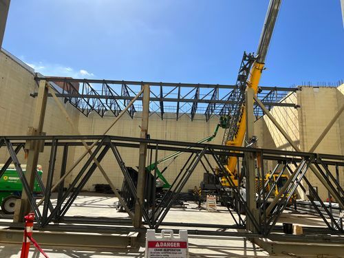 Newly engineered roof support being lifted into place by a crane.