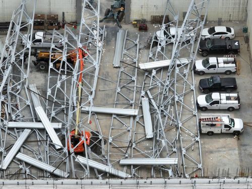 Steel from a collapsed roof laying on top of boom lifts and trucks in a warehouse.