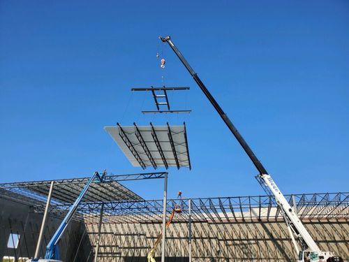 A crane lifting a section of roof into place on a warehouse.